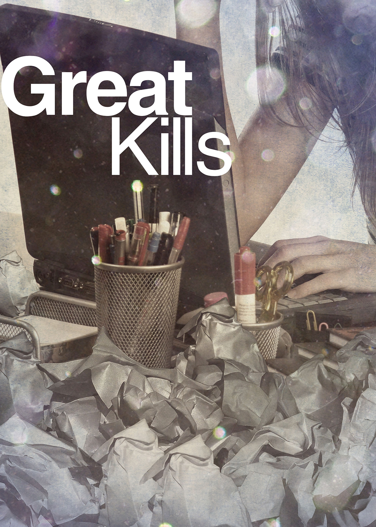 Key Art from Great Kills (2015). An image of a woman at a laptop. There is a jar of pens and pencils next to the laptop. Balls of crumbled paper are thrown around the table the woman is sitting at.