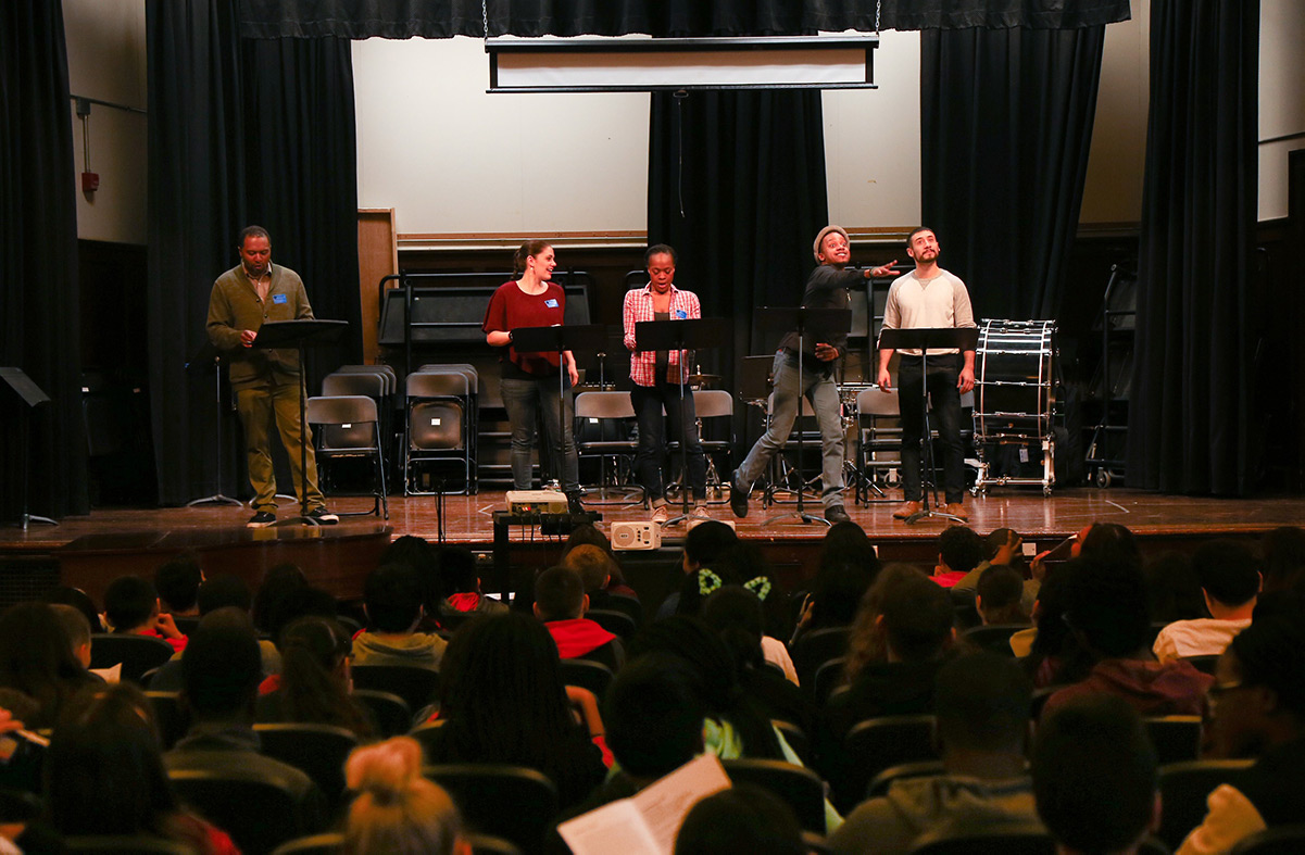 Two actors perform a play while the student writers watch